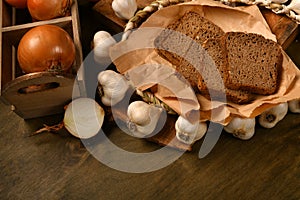 Still life of food in a rural style on a dark wood background, rye bread and garlic, tomatoes and onion, concept of fresh