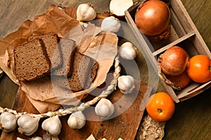 Still life of food in a rural style on a dark wood background, rye bread and garlic, tomatoes and onion, concept of fresh