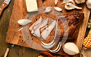 Still life of food in a rural style on a dark wood background, sliced lard and garlic, cheese, corn and onion, concept of fresh