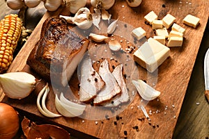 Still life of food in a rural style on a dark wood background, sliced lard and garlic, cheese, corn and onion, concept of fresh