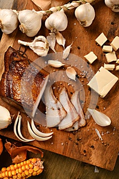 Still life of food in a rural style on a dark wood background, sliced lard and garlic, cheese, corn and onion, concept of fresh
