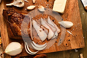 Still life of food in a rural style on a dark wood background, sliced lard and garlic, cheese and onion, concept of fresh