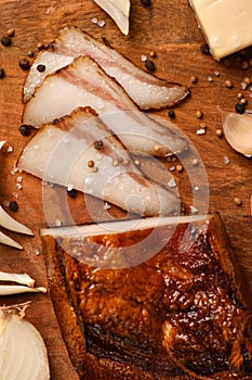 Still life of food in a rural style on a dark wood background, sliced lard and garlic, cheese and onion, concept of fresh