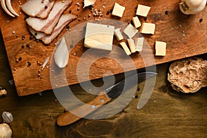 Still life of food in a rural style on a dark wood background, sliced lard and garlic, cheese and onion, concept of fresh