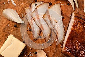 Still life of food in a rural style on a dark wood background, sliced lard and garlic, cheese and onion, concept of fresh