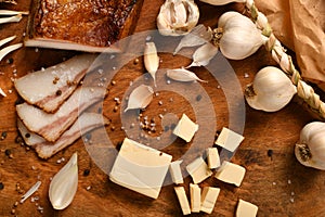 still life of food in a rural style on a dark wood background, sliced lard and garlic, cheese and onion, concept of fresh