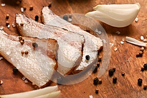 Still life of food in a rural style on a dark wood background, sliced lard and garlic, salt and pepper, concept of fresh