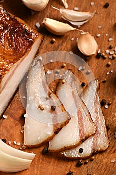 Still life of food in a rural style on a dark wood background, sliced lard and garlic, salt and pepper, concept of fresh