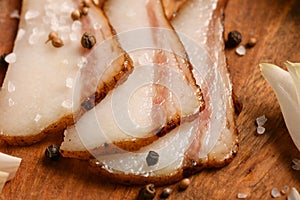 Still life of food in a rural style on a dark wood background, sliced lard and garlic, salt and pepper, concept of fresh