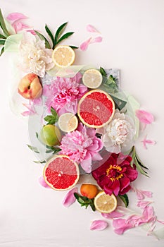 Still life with fresh assorted exotic fruits and peony flowers on white background. Festive flower and fruit composition. Wedding