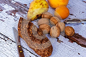 Still life with fresh bread with cereals, walnuts, pear, peach and apricot