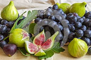 Still life of fresh colorful fruits. Bunch of black grapes, green figs on a light background.
