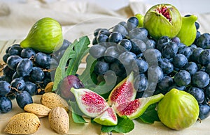 Still life of fresh colorful fruits. Bunch of black grapes, green figs on a light background.