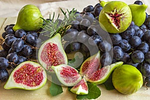 Still life of fresh colorful fruits. Bunch of black grapes, green figs on a light background.