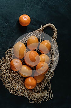 Still life with fresh lemons in a cotton string bag on a black .