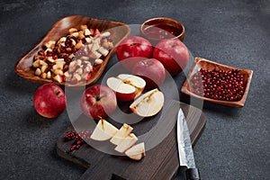 Still life with fresh lingonberries, red appples with knife on black cutting board and homemade jam on dark background. Top view