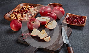 Still life with fresh lingonberries, red appples with knife on black cutting board and homemade jam on dark background. Top view