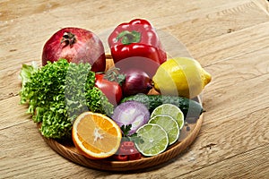 Still life of fresh organic vegetables on wooden plate over wooden background, selective focus, close-up