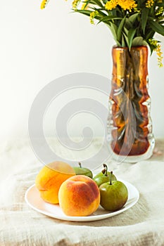 Still life with fresh peaches and plums on linen cloth background on wooden table. Bright juicy summer fruits