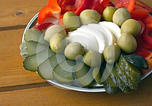 Still life with fresh and pickled vegetables on the plate on a wooden surface