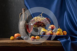 Still life with fruit and a bottle of wine. Apples, pears, plums, grapes and nectarines.