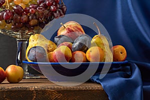 Still life with fruit and a bottle of wine. Apples, pears, plums, grapes and nectarines.