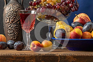 Still life with fruit and a bottle of wine. Apples, pears, plums, grapes and nectarines.