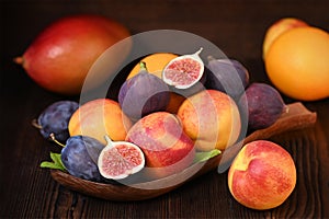 still life with fruit on a wooden background, nectarines, plums, figs, orange, mango