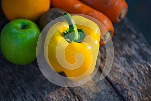 Still life fruit with yellow bell pepper green apple carrot orange and kiwi on rustic wood