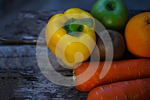 Still life fruit with yellow bell pepper green apple carrot orange and kiwi on rustic wood