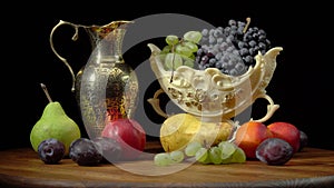 Still life with fruits on a round wooden table and black background.