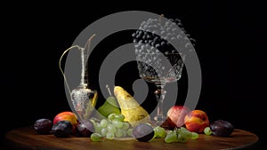 Still life with fruits on a round wooden table and black background.