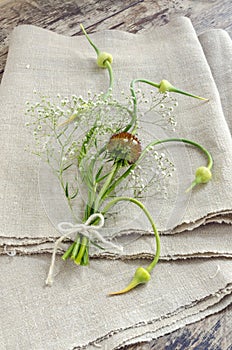 Still life with garlic buds and bouquet flowers on linen tablecloths