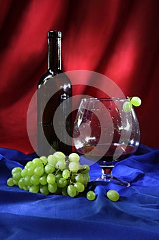 Still life with glass of good red wine and bunch of grapes