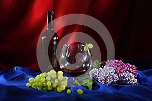 Still life with glass of red wine, bunch of grapes and lilac