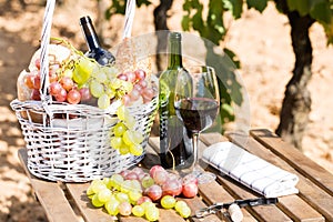Still life with glass of red wine grapes and picnic basket on ta