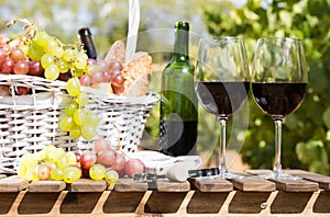 Still life with glass of red wine grapes and picnic basket on table