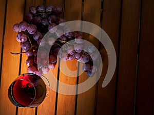 Still life, glass of red wine and red grapes on a wooden table. Warm tone. Top view