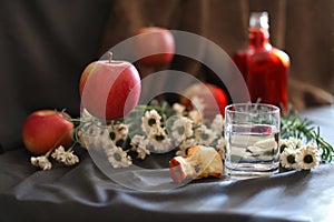 still life, a glass of water, a core and ripe apples, decorative flowers, one apple hanging in the air