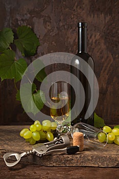 Still life with glass of white wine and grapes on vintage wooden background