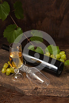 Still life with glass of white wine and grapes on vintage wooden background