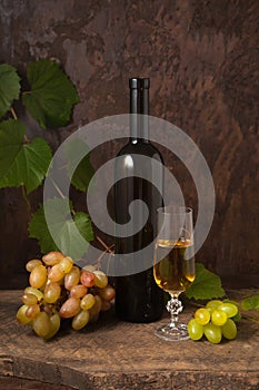 Still life with glass of white wine and grapes on vintage wooden background