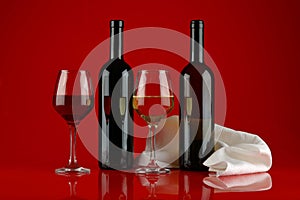 Still life with glasses of wine on a red, glossy background