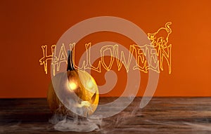 Still life with glowing Jack lantern with smoke on a wooden table on a blood-orange background with the inscription Halloween