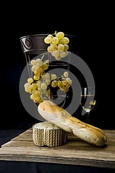 Still life with golden grapes and and white wine on black background