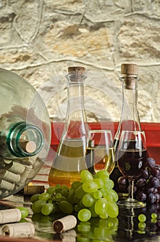 Still life with grapes, wine glasses and wine bottles in old cellar
