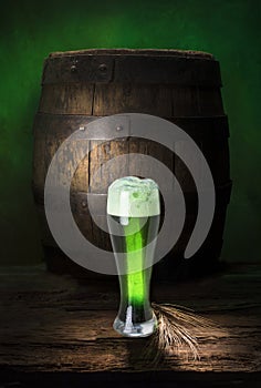 Still life with green beer on old wood and barrel
