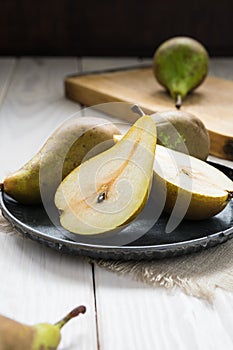 still life, green pears in a metal plate on a white wooden table