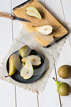 still life, green pears in a metal plate on a white wooden table, top view