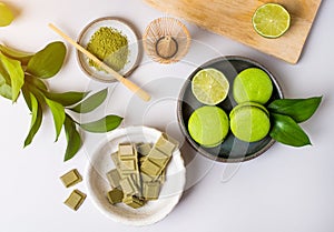Still life with green products: macarons almond cakes, matcha tea, green vegan chocolate, lime